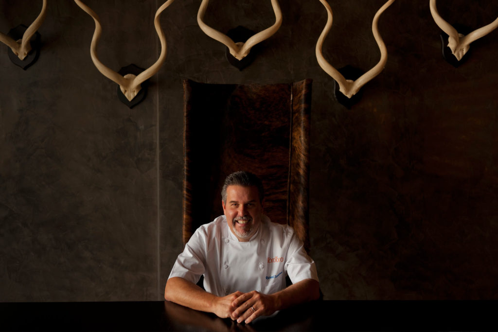 Chef Richard Sandoval smiling white sitting at table