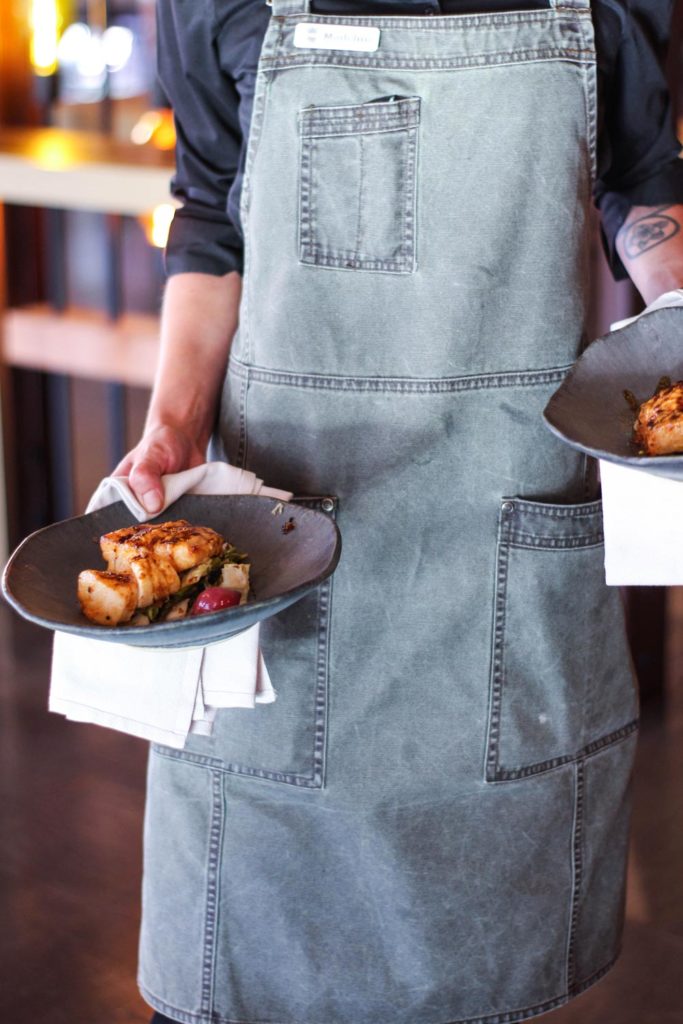 restaurant server in apron serving two dinner dishes